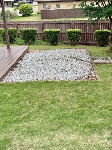 This spacious yard offers a perfect blend of natural greenery and functional outdoor living space.