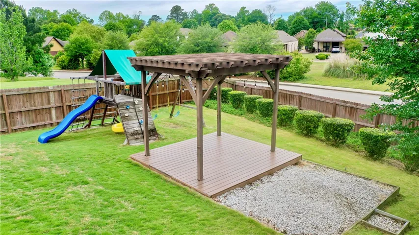 This spacious yard features a pergola, perfect for outdoor enjoyment, alongside a fun play area.