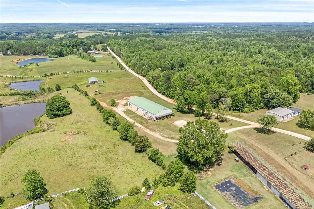 Expansive rural property with multiple outbuildings, tranquil ponds, and lush woodlands.