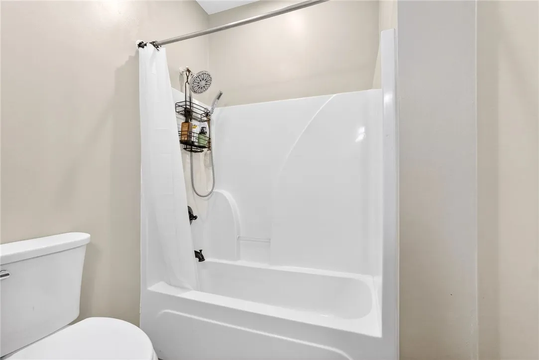 This bathroom features a sleek, white tub and shower combination.