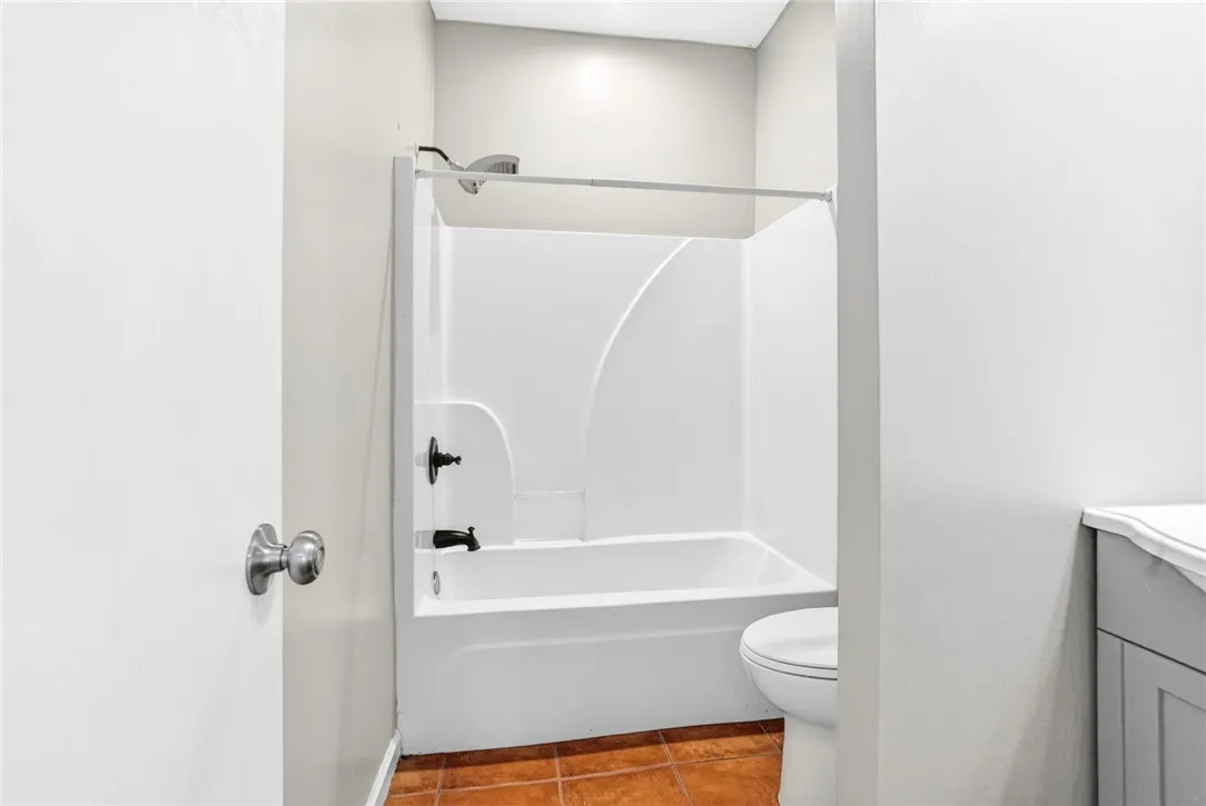 This bathroom features a shower-tub combination and classic tile flooring.