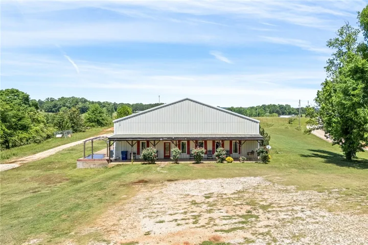 This expansive rural property offers a wide front porch and a vast, open landscape.