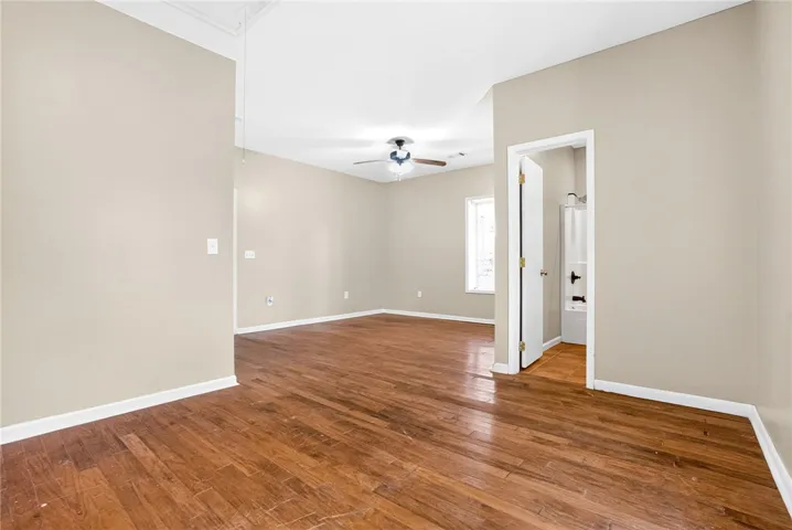 This airy room features rich hardwood flooring and a ceiling fan, offering comfortable living.