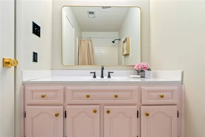 This bathroom features a single vanity with a sleek sink and classic fixtures.
