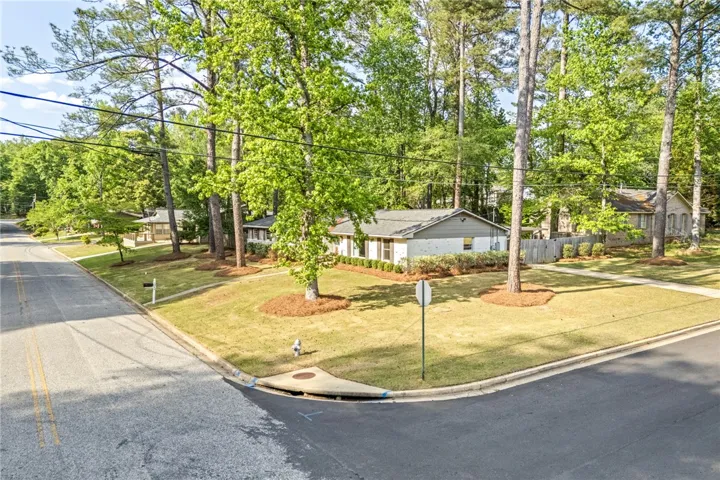 This charming home features a well-maintained lawn, lush trees, and classic brick construction.