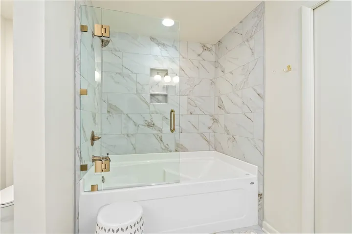 This sleek bathroom features a modern bathtub with a glass enclosure.