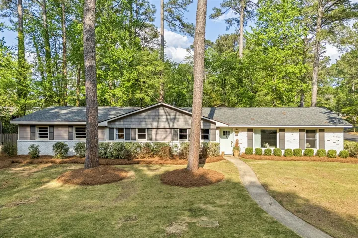 This charming home offers a welcoming facade with a lush, verdant setting.