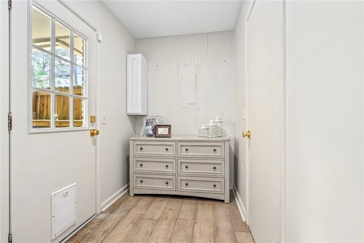 This bright mud room features a windowed door and wood flooring.