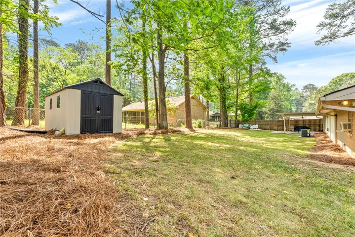 This spacious yard features lush green grass and a functional storage shed.