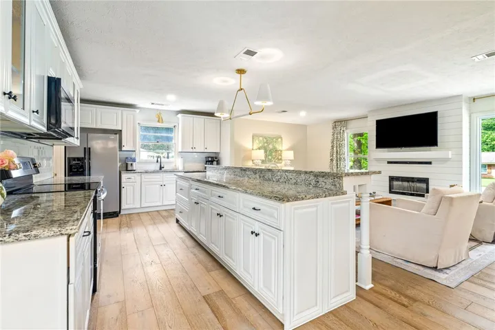 This kitchen features a large island and ample counter space, seamlessly connecting to the adjacent living area.