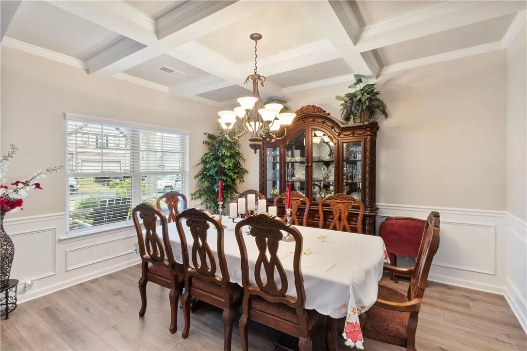 This elegant dining area boasts beautiful wainscoting, crown molding, and stylish flooring.