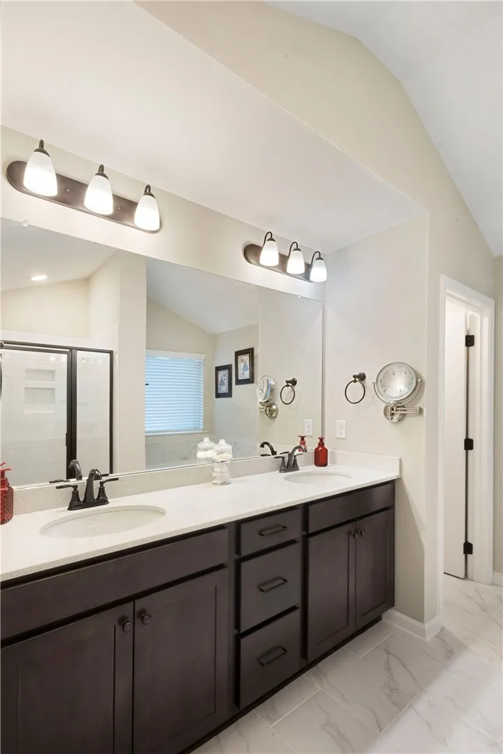 This bathroom features a double vanity and a spacious shower, combining both style and convenience.