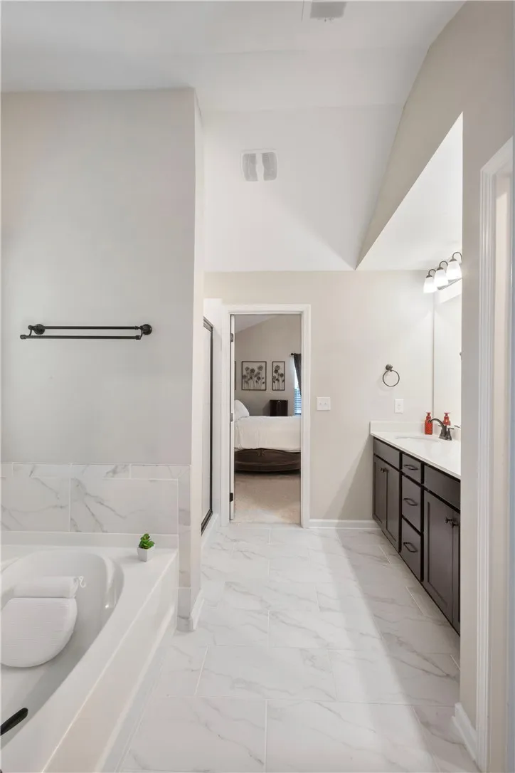 This serene bathroom offers a spacious retreat with elegant tiling and vaulted ceilings.