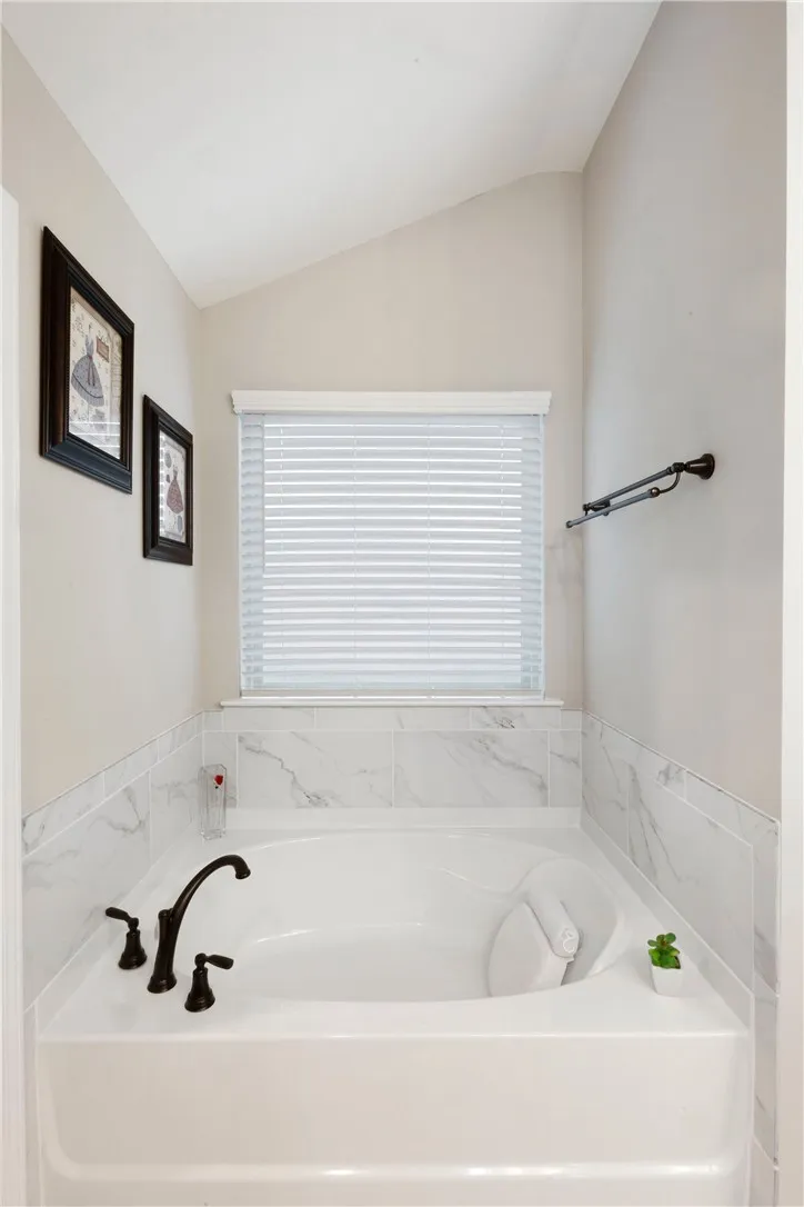 This primary bathroom features a deep soaking tub with elegant tile surround and a window for natural light.