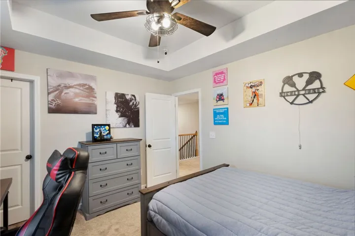 This cozy bedroom features a stylish ceiling fan and soft carpeting, creating a comfortable living space.