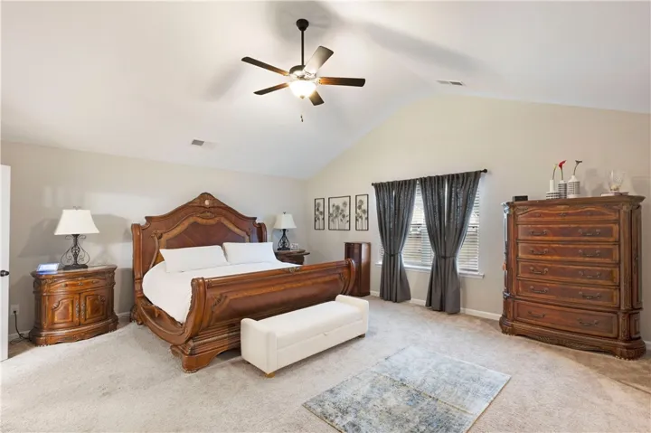This spacious bedroom offers high ceilings and comfortable carpet flooring, perfect for relaxation.