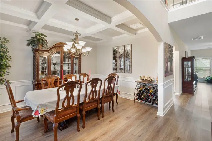This elegant dining room features rich flooring and distinctive coffered ceilings, creating a refined atmosphere.