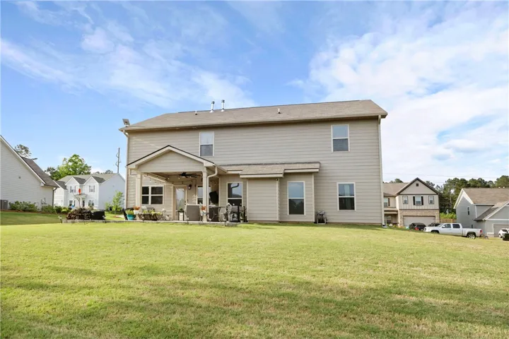 This residence features an expansive backyard with a comfortable covered patio, perfect for outdoor living.