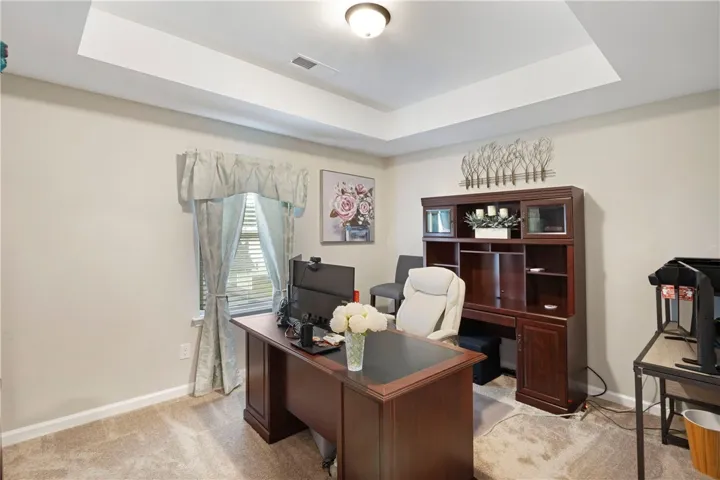 This bedroom features plush carpeting and a tray ceiling.