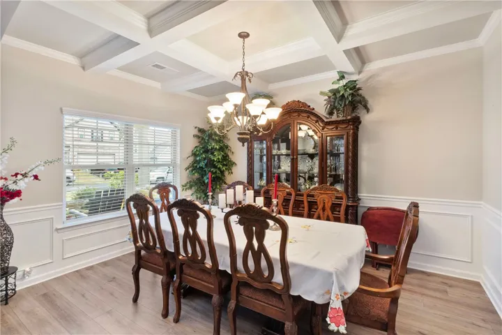 This elegant dining area boasts beautiful wainscoting, crown molding, and stylish flooring.