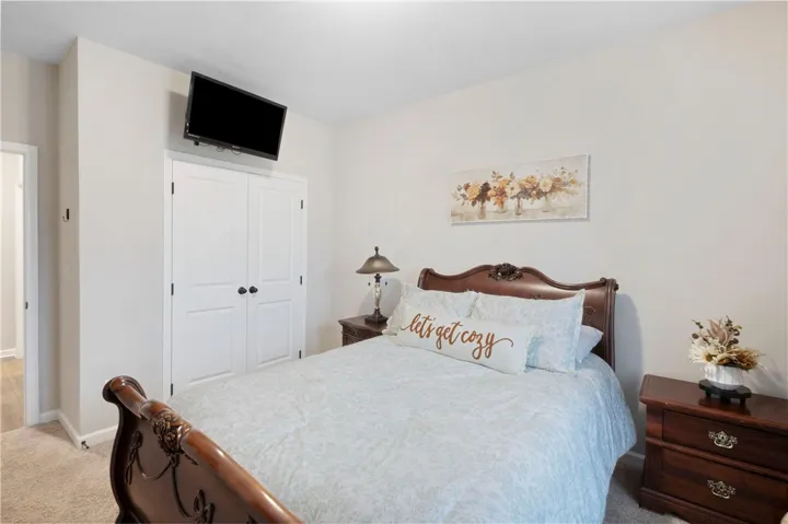 This inviting bedroom features neutral tones and comfortable carpeting.