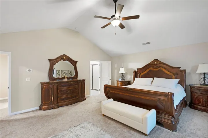 This spacious primary bedroom features vaulted ceilings, soft carpet, and easy access to the primary bathroom.