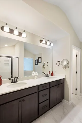This bathroom features a double vanity and a spacious shower, combining both style and convenience.