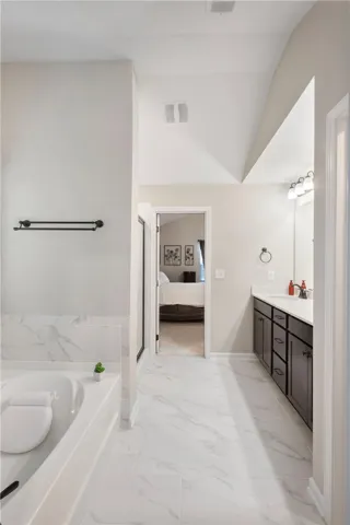 This serene bathroom offers a spacious retreat with elegant tiling and vaulted ceilings.