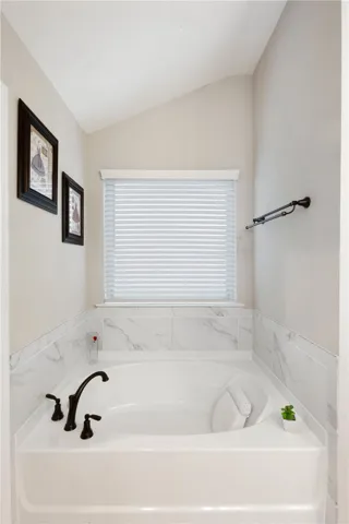 This primary bathroom features a deep soaking tub with elegant tile surround and a window for natural light.