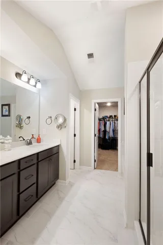This spacious bathroom offers elegant flooring and a well-appointed vanity with convenient access to a walk-in closet.