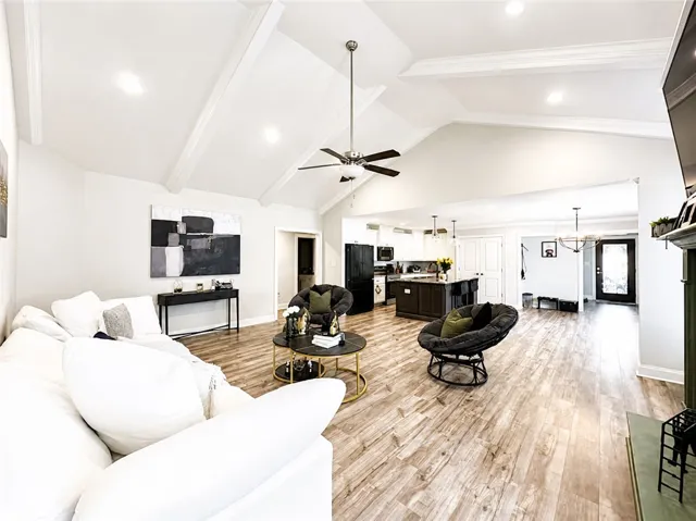 This expansive great room seamlessly blends living and kitchen spaces with vaulted ceilings and wood flooring.