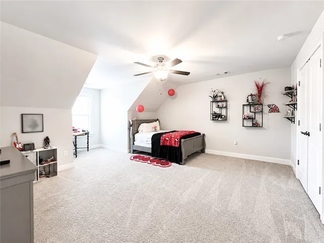 This expansive bedroom offers comfortable carpeting and sloped ceilings, perfect for a cozy retreat.