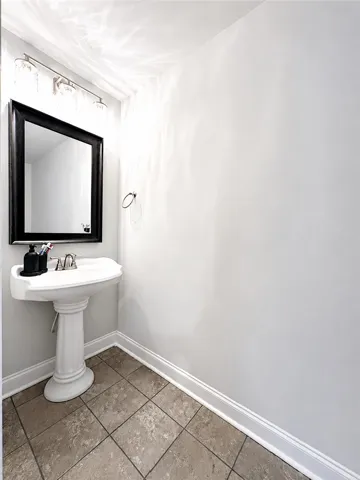 This clean and bright powder room features a pedestal sink and tiled flooring.