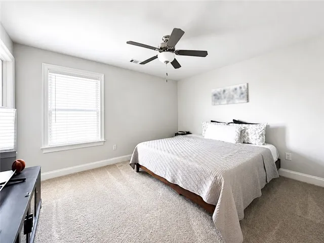 This cozy bedroom features soft carpet and ample natural light, creating a serene personal retreat.