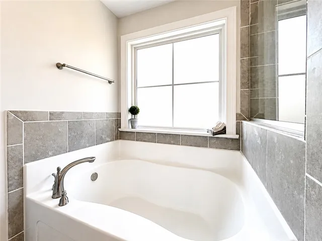 Relax in this inviting tub, featuring sleek design and ample natural light.