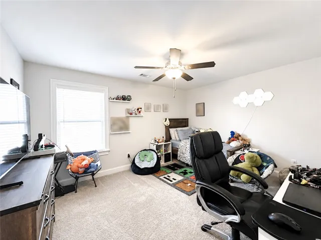 This inviting bedroom features carpeted flooring and a ceiling fan, creating a comfortable and functional space.