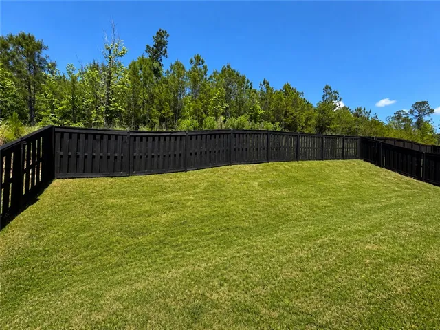 This spacious yard features a sturdy privacy fence and ample green space for outdoor enjoyment.