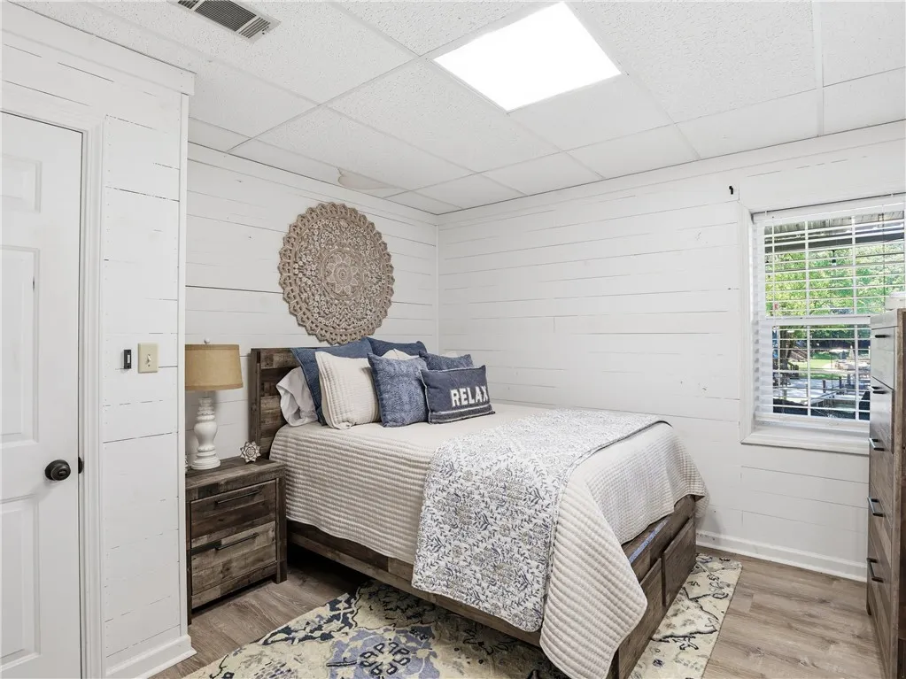 This inviting bedroom features planked walls and ample natural light, creating a comfortable retreat.