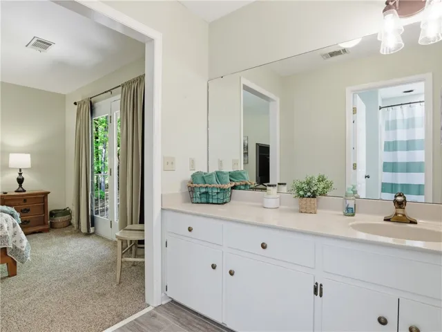 This primary bathroom features an expansive mirror, spacious vanity, and a refreshing outdoor view.
