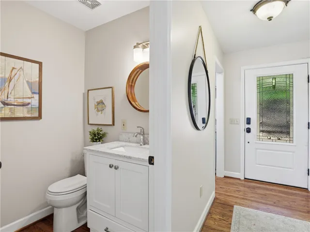 This bathroom features hardwood floors and a single vanity, offering both practicality and charm.