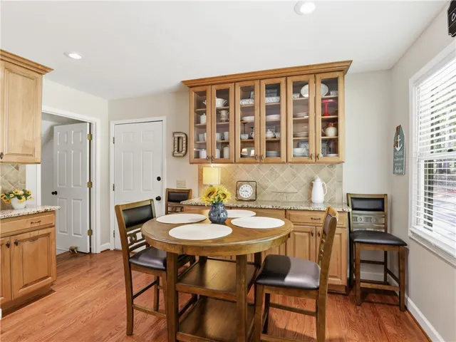 This kitchen showcases warm cabinetry, granite countertops, and elegant tile backsplash, creating a charming and inviting atmosphere.
