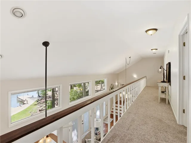 This interior hallway features carpet flooring and vaulted ceilings.
