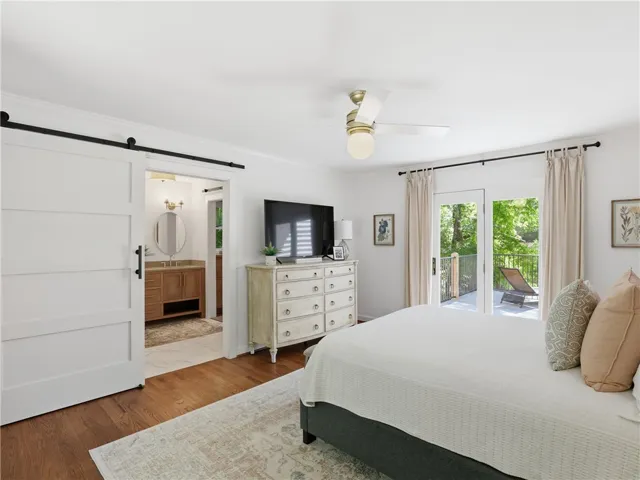 This tranquil bedroom features outdoor access, a beautiful bathroom, and sleek hardwood floors.