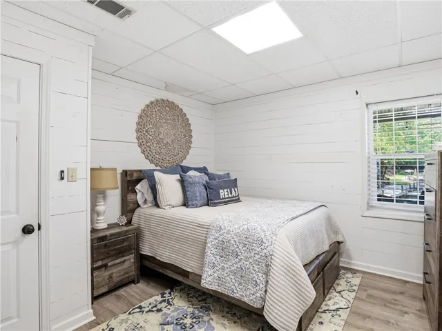 This inviting bedroom features planked walls and ample natural light, creating a comfortable retreat.