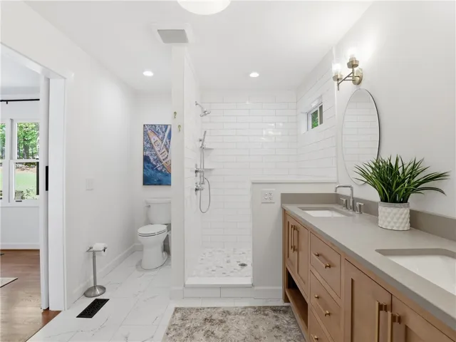 This bright bathroom features a spacious shower and a vanity with dual sinks.