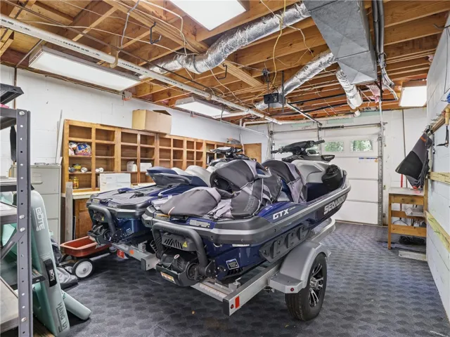 This spacious garage offers ample room for vehicles and storage, featuring an exposed beam ceiling.