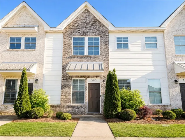 This charming townhome presents an appealing facade with brick and siding, featuring neatly landscaped grounds.