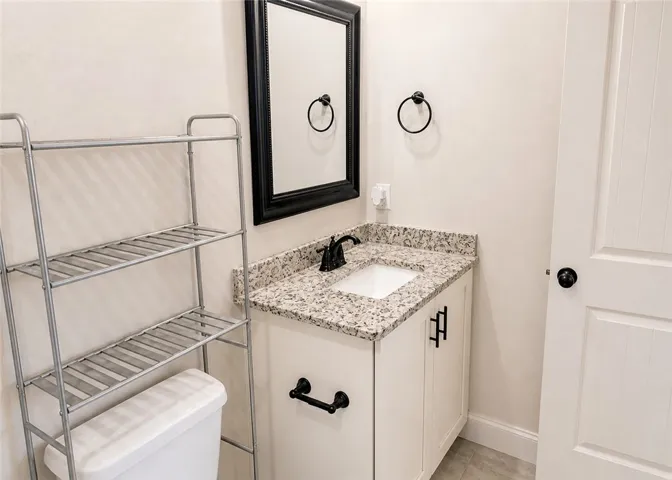 This bright bathroom features a vanity with granite counters and a clean design.