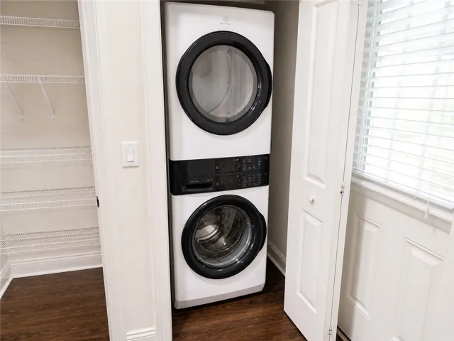 This dedicated laundry space features convenient stacked appliances and durable wood flooring.