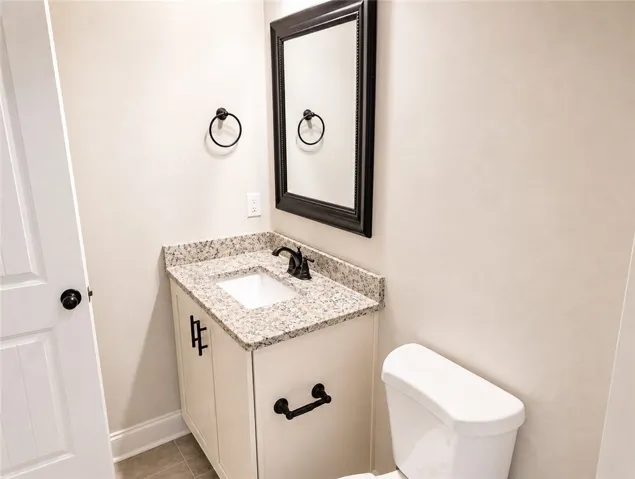 This bright bathroom features a vanity with granite counters and a clean design.